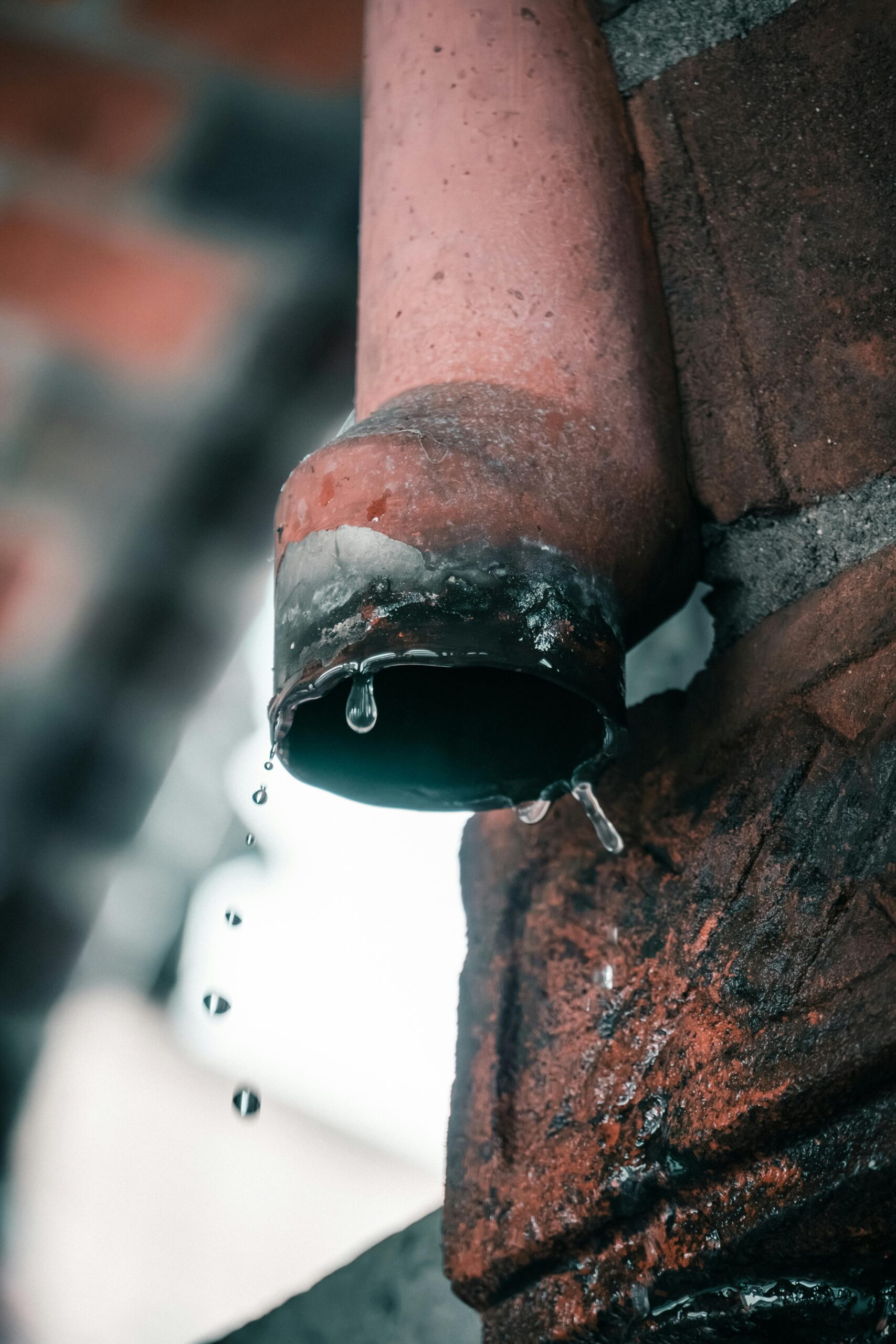 Close-up of a rusty water pipe dripping droplets, capturing urban decay in Berlin.